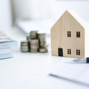 picture with small wooden house, stacked coins, real estate investment 2025